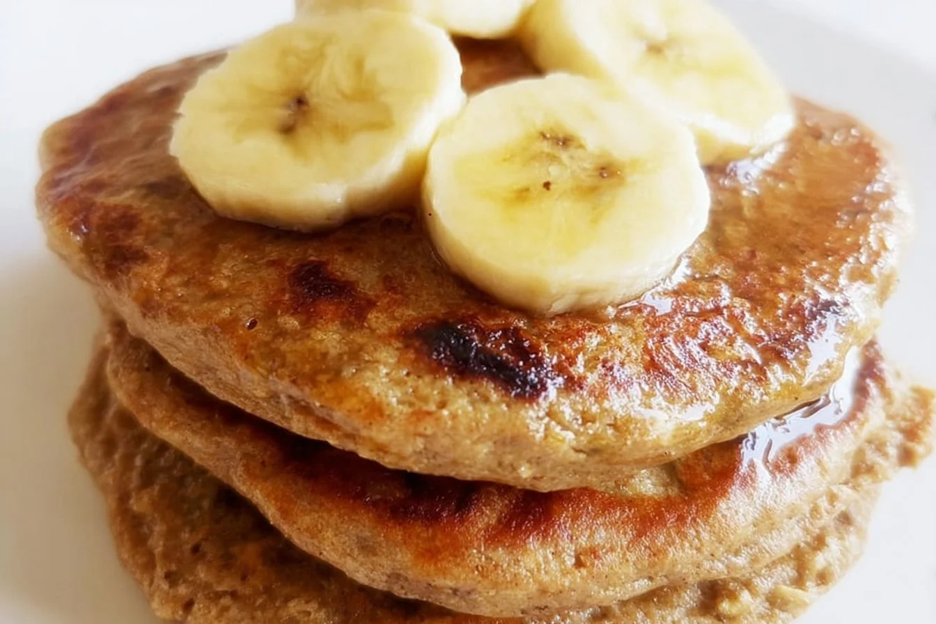 Delicious banana oatmeal pancakes stacked on a plate with syrup