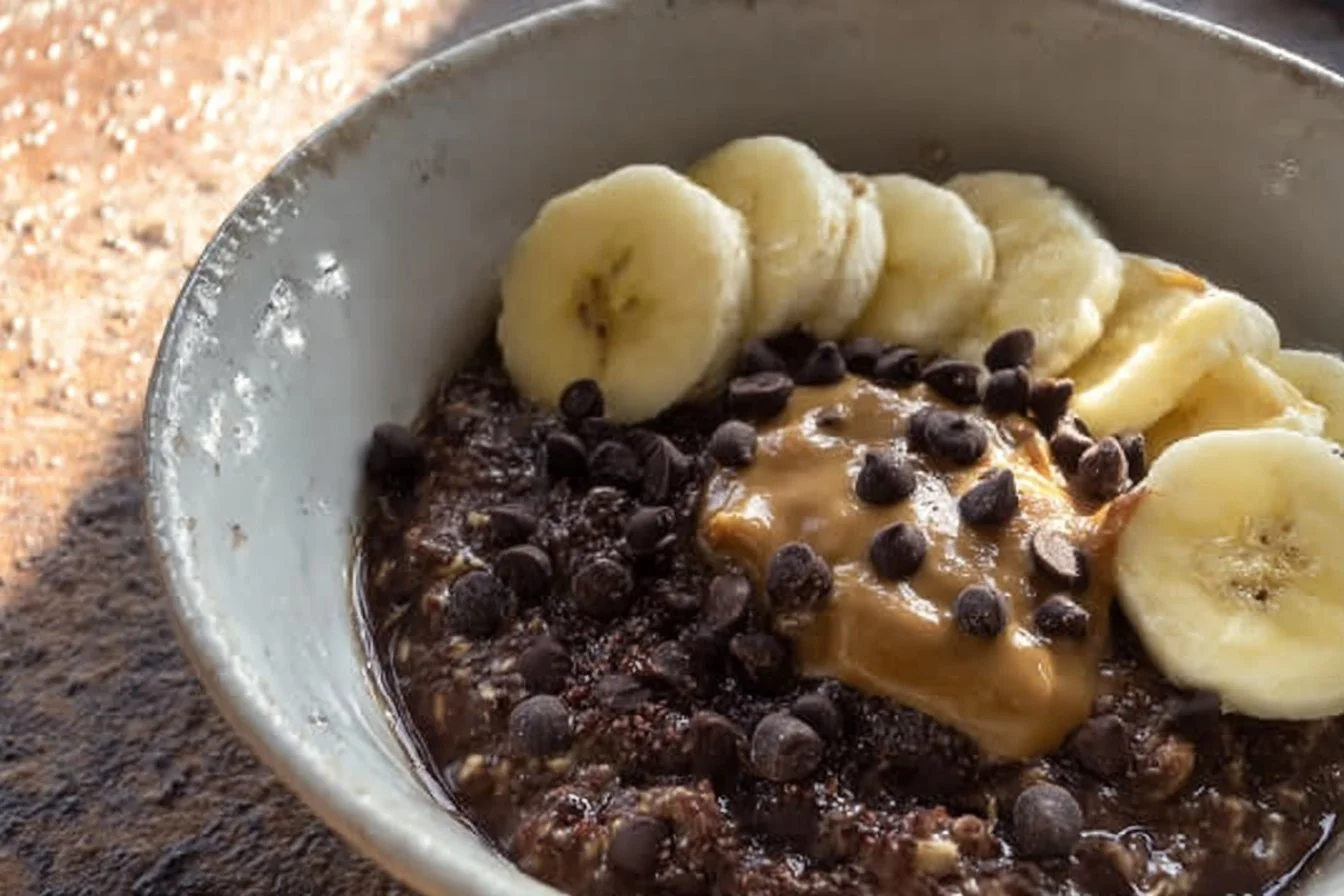 Bowl of chocolate oatmeal topped with fruits and nuts
