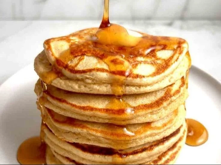 Stack of fluffy high-protein pancakes topped with fresh berries and maple syrup